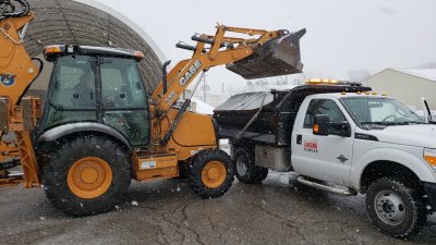 Photo of a backhoe loading a snowplow 